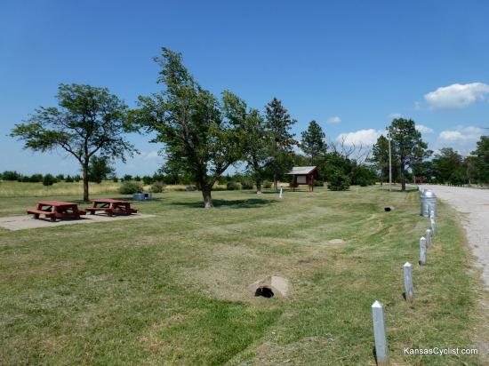US-54 Rosalia Roadside Park - This is a view of the Rosalia Roadside Park from the turnout road. It shows picnic tables, trash cans, fire pits, an information kiosk, and non-functioning water fountains.